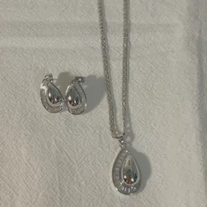 Silver-tone teardrop pendant necklace and earrings set with sparkling cubic zirconia.