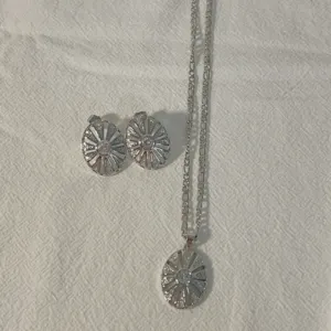 Gedetailleerd van zilverkleurige zirkonia zonnestraal kompas ketting en oorbellen set.