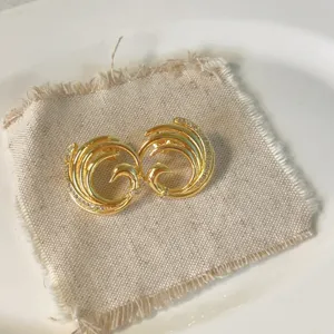 Primo piano dettagliato di orecchini a perno con zirconi e rame 18k su tessuto di lino.