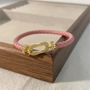 Pink braided leather bracelet with gold pave diamond horseshoe clasp accessory for couples.