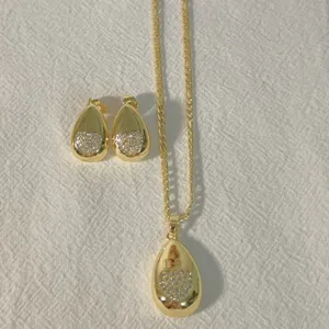 Detailed view of gold plated teardrop pendant necklace and matching pave heart earrings set.