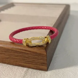 Red braided leather bracelet with gold pavé crystal horseshoe clasp, elegant couple jewelry.