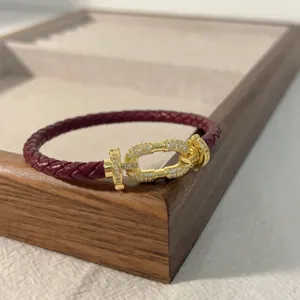 Red braided leather bracelet with gold-paved horseshoe buckle for daily couple wear.