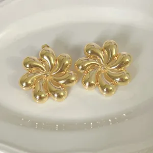 Vista dettagliata di orecchini dorati creativi a forma di fiore a spirale, eleganti.