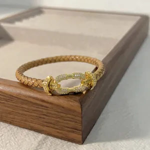 Braided leather bracelet with gold horseshoe micro pave cubic zirconia clasp detail.