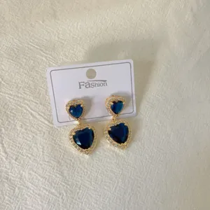 Close-up of double-layer heart blue gemstone earrings with rhinestones on white card.
