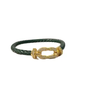 Green braided leather bracelet with gold-tone pave rhinestone horseshoe buckle for daily wear.