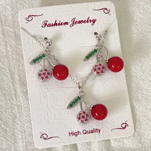 Kirschen Halskette und Ohrringe Schmuckset Detail, roter Frucht Anhänger mit grünen Blättern.