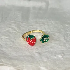 Vista dettagliata di anello aperto con fragola smaltata, grazioso gioiello in rame regolabile.