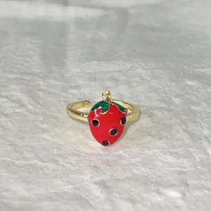Primo piano dettaglio anello aperto smalto fragola dolce, design frutta carino, regolabile.