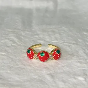 Anello aperto in rame dorato con charm di fragole rosse, foglie verdi e pietre lucide.