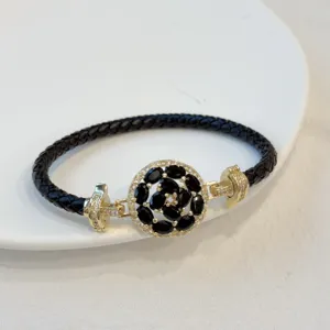 Black braided leather bracelet featuring 18k gold plated black floral zircon centerpiece detail.