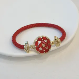 Detail shot of the red braided leather bracelet featuring a sparkling zircon floral clasp.