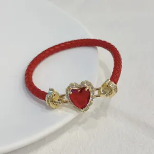 Close-up detail of the red braided leather bracelet featuring a sparkling red heart zircon crystal.