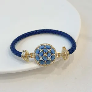 Detailed shot of the luxury blue leather bracelet featuring a gold-plated circular crystal centerpiece.