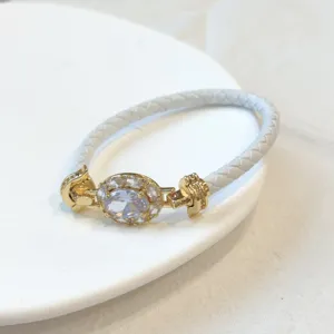 Primo piano del bracciale in pelle intrecciata bianca con zircone ovale placcato oro.