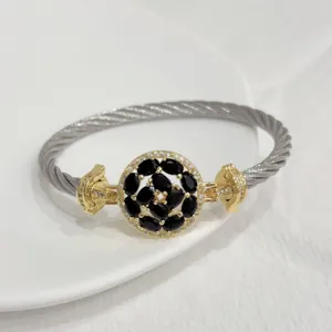Detailed view of copper 18k gold plated cable cuff bracelet with black zircon flower charm.