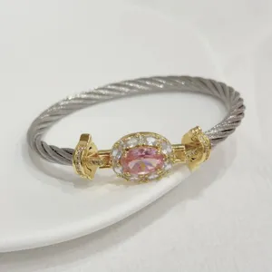 Close-up of the pink cubic zirconia cable bangle, showcasing the gold plated twisted wire detail.