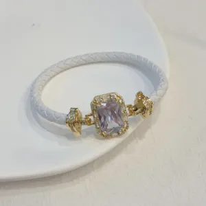 Vista dettagliata di bracciale intrecciato in pelle bianca zircone placcato oro.