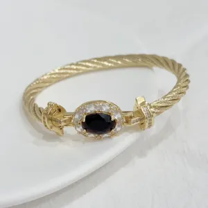 Luxurious 18K gold plated cable twist bracelet with oval dark stone and sparkling cubic zirconia.