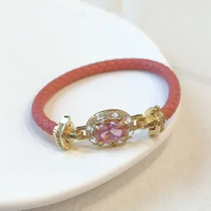 Vista dettagliata del lussuoso bracciale in pelle rosa intrecciata con zircone ovale.