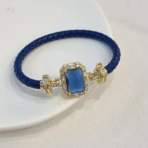 Lussuoso bracciale in pelle intrecciata blu con chiusura dorata e zirconi scintillanti.
