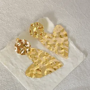 Nahaufnahme Detailansicht gehämmert goldener geometrischer Ohrringe, Vintage Metall Design.
