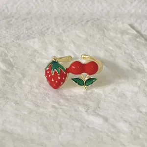 Gedetailleerde close-up van een schattige aardbei en kers geëmailleerde open ring, felle kleuren.