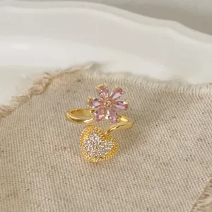 Close-up detail van vergulde open ring met roze kristallen bloem en pave hartje.