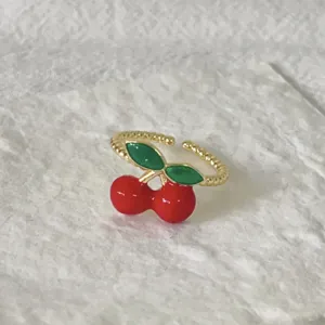 Charmante vergulde open ring met een leuk rood kersenontwerp en groene emaillen bladeren.