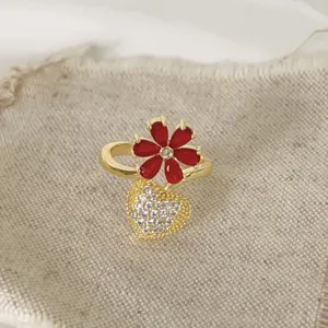Gouden ring detail met schitterende rode bloem en een fonkelende kristallen hart hanger.