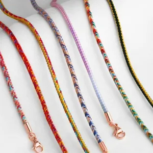 Close-up detail of colorful handmade braided cord necklaces with rose gold lobster clasps.