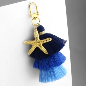 Blue gradient cotton tassel starfish keychain bag charm, elegant gold metal lobster clasp.