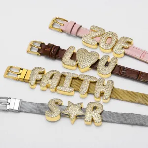 Detailaufnahme von klobigen Zirkonia Buchstaben Anhängern auf verschiedenen Uhrenarmbändern.