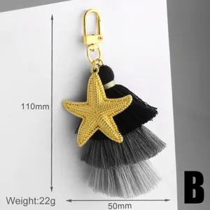 Pendentif étoile de mer dorée avec un pompon noir multicouche détail de porte-clés.
