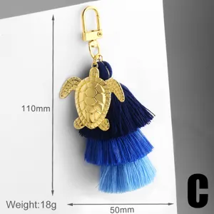 Porte-clés pompon bleu avec pendentif tortue dorée, charm élégant pour sac à main.