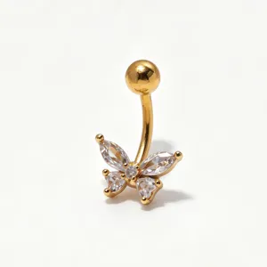 Primo piano di un piercing per ombelico in acciaio dorato con farfalla in zircone brillante.