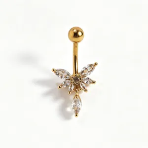 Primo piano dettagliato di un piercing ombelico dorato con zircone e ciondolo.