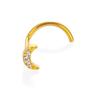 Close-up detail of gold titanium crescent moon nose stud with sparkling cubic zirconia stones.