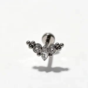 Gedetailleerde close-up van titanium kraakbeen piercing met gebogen zirkonia cluster.
