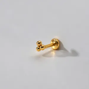 Goldfarbenes Titan Drei-Kugel Cluster Labret Piercing Detail, glattes und elegantes Design.