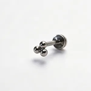Detailaufnahme eines eleganten Piercing-Schmucks aus Titan mit einem einzigartigen 3-Kugel-Design.