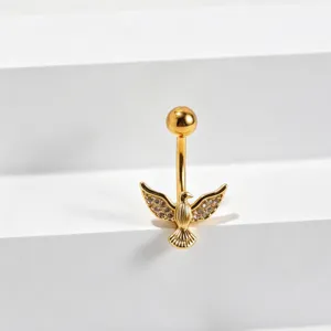 Primo piano dettagliato di un piercing ombelico dorato con uccello in zirconi luminosi.