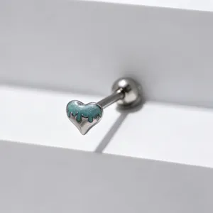 Stainless steel tongue ring barbell with glitter teal heart detail, macro shot of jewelry craft.