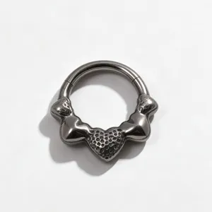 Close-up detail of titanium piercing ring with textured heart charm for septum and ear cartilage.