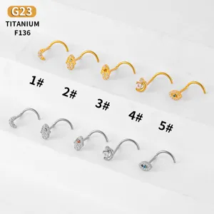 Detailed view of titanium nose studs with moon and hamsa hand designs, zirconia piercing rings.
