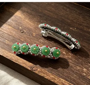 Primo piano di molletta per capelli a loto in finta giada cinese con perle e perline rosse.