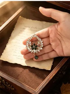 Vintage emerald crystal wreath brooch with teardrop pendant, elegant retro coat accessory.
