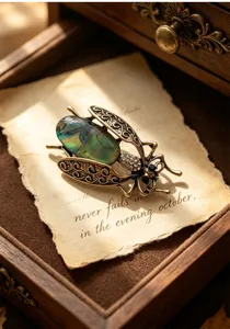 Vintage abalone shell insect brooch close-up, intricate metal filigree wings, retro suit lapel pin.