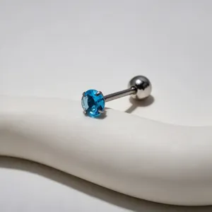 Close-up view of a stainless steel tongue piercing featuring a vibrant blue zircon stone detail.